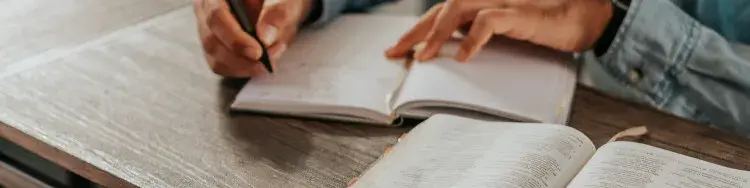 una mujer escribiendo en una libreta al lado de su biblia