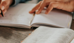 una mujer escribiendo en una libreta al lado de su biblia